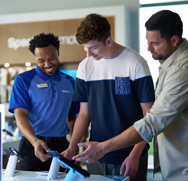 Spectrum store team and customers smiling at a phone display