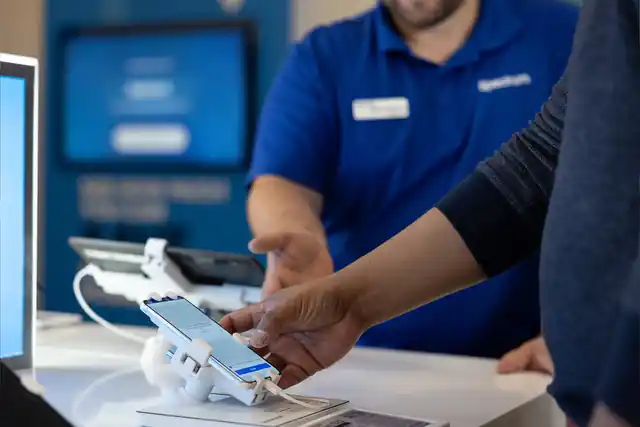 Store associate helping a customer try a phone at a Spectrum display